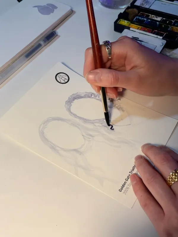 Natalie's hand painting a guest portrait on card stock printed with the client's event logo and name