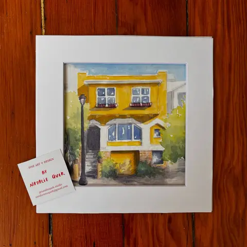 The finished watercolor house portrait matted and ready to hand over, with Natalie's hand-lettered business card resting on the mat