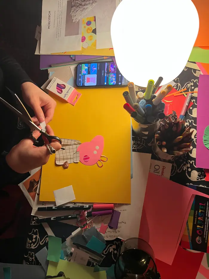 A participant cutting paper for a colorful collage at a table covered with art materials.