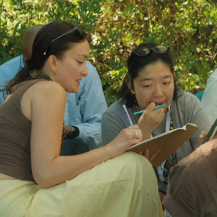 Natalie helping a participant with a sketchbook during an outdoor workshop.