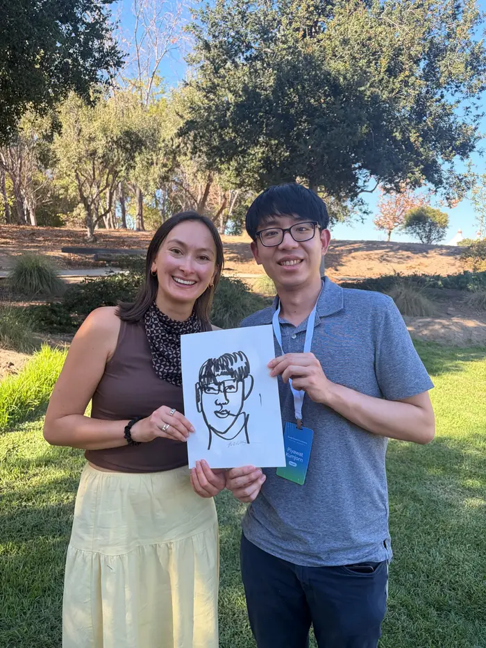 Natalie and a smiling workshop participant holding a line portrait outdoors.