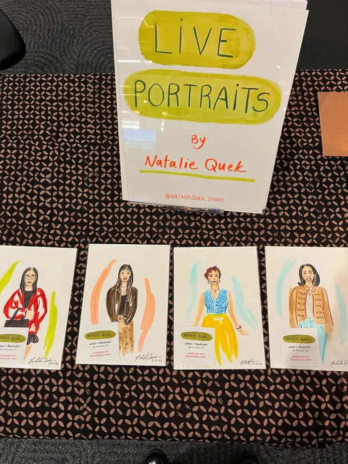 Colorful fashion portraits displayed beneath a handwritten Live Portraits by Natalie Quek sign