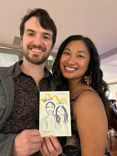 Smiling couple holding their illustrated double portrait at an event